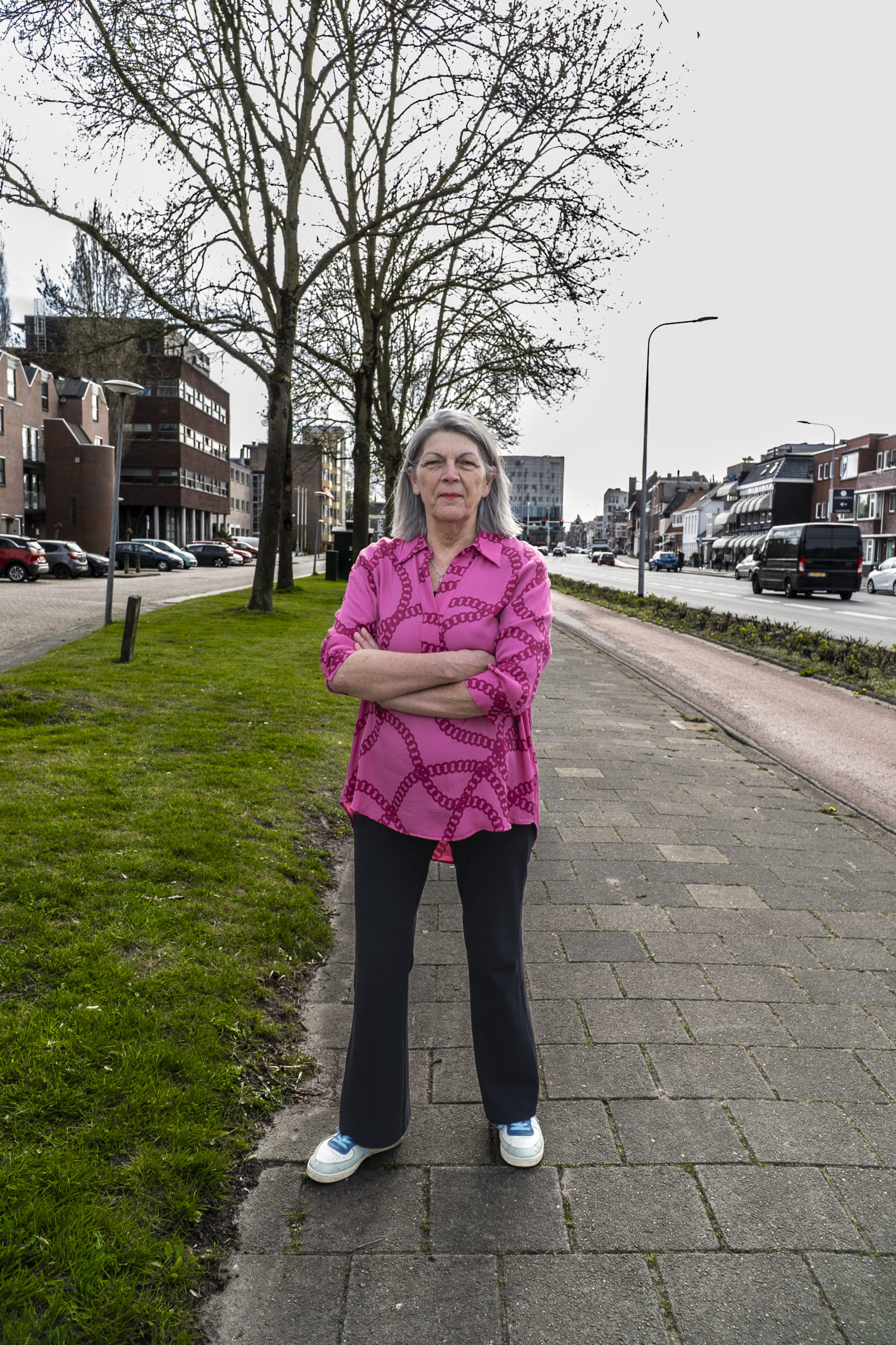 Foto van vrouw met roze shirt en witte schoenen op de stoep ( damsterdiep )